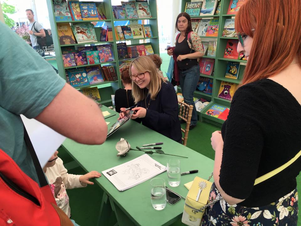 Michelle is smiling as she chats to a family while signing books at Edinburgh Book Festival.